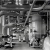 men inside large hall containing pipes and machinery